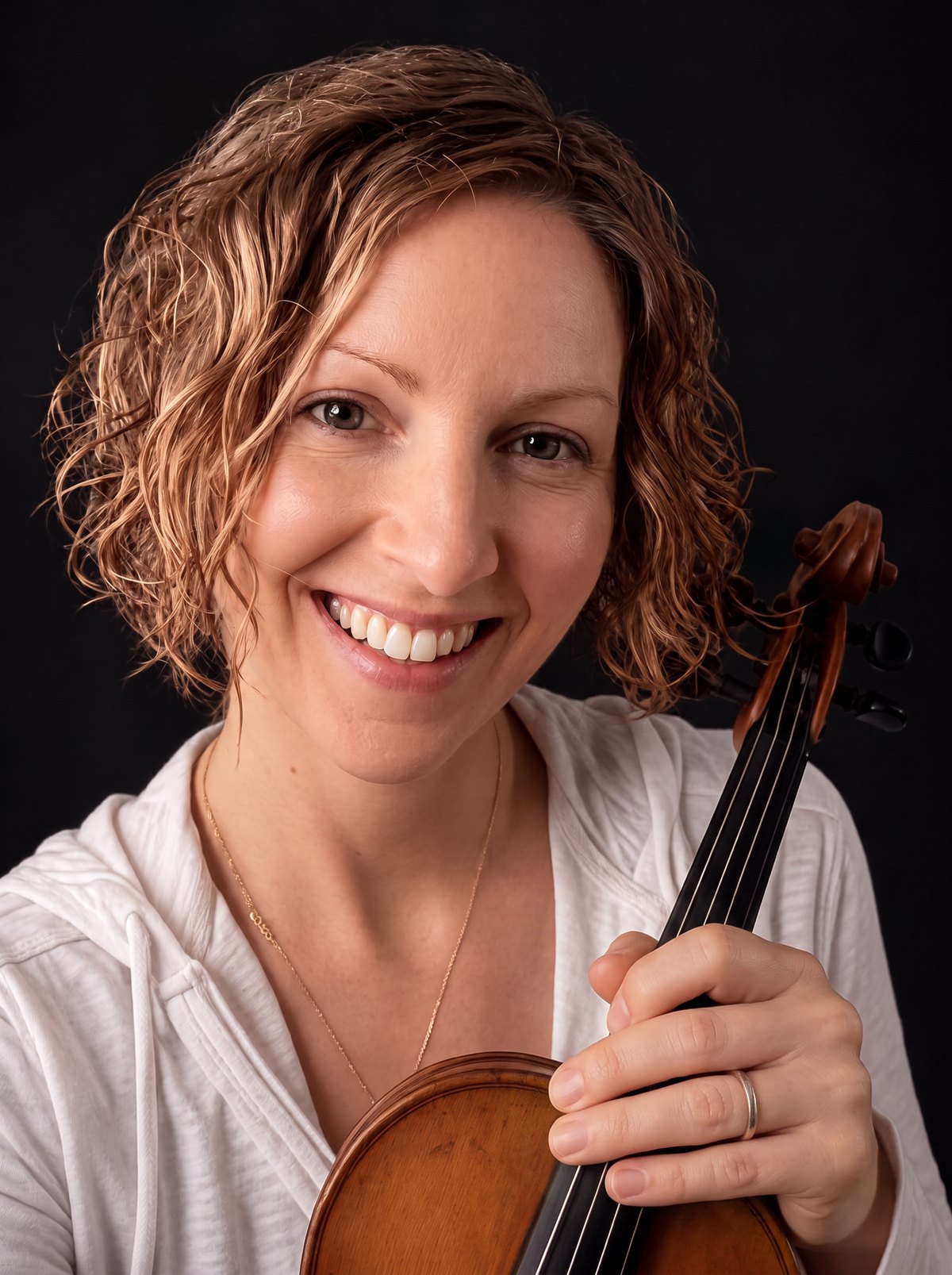 Dr. Amanda Smith Roberts smiling warmly, holding her violin.